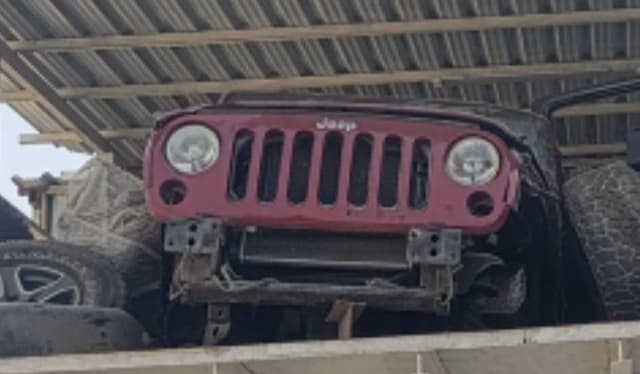 Red Jeep Wrangler front cut — seven-slot grille, round headlights and radiator support, Sharjah market