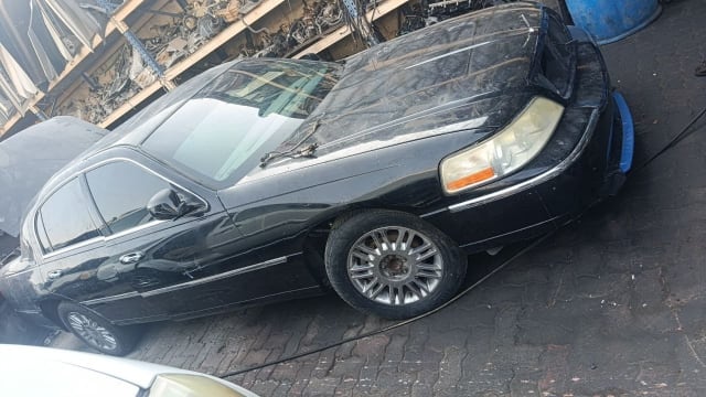 Black Lincoln Town Car sedan for parts — headlight, hood, fender, doors and alloy wheel, Sharjah market