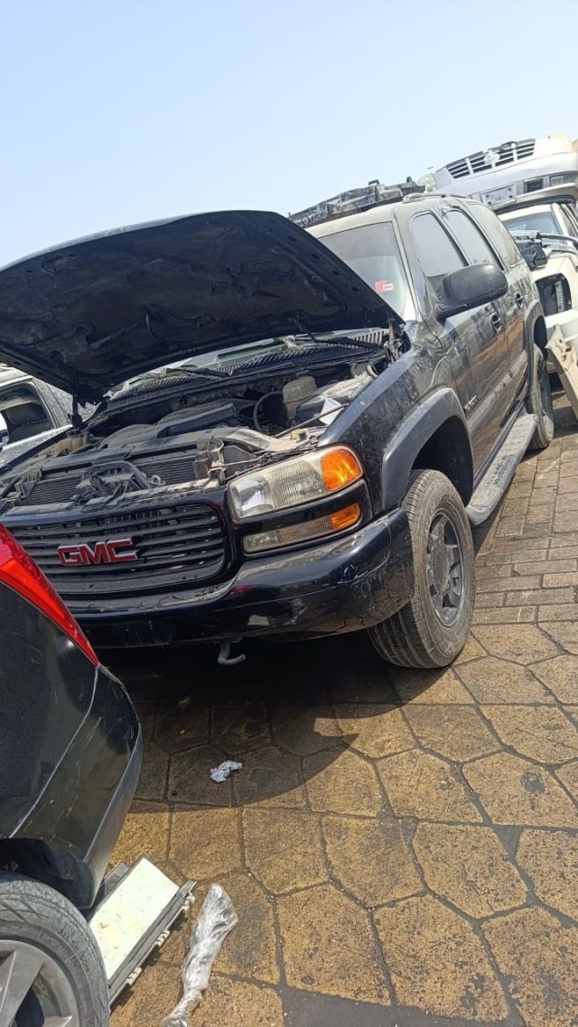 Black GMC Yukon SUV for parts — open hood, grille, headlights and engine bay, Sharjah market