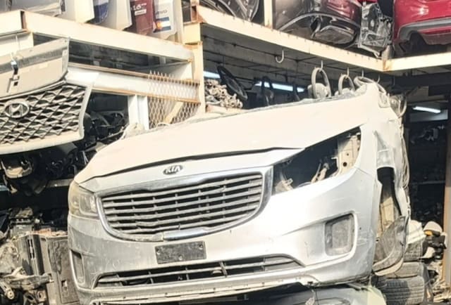 Silver Kia Sedona / Carnival minivan front cut — bumper, chrome grille and hood, Sharjah market