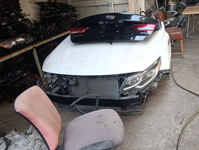 White Kia Optima front cut — hood, headlights and radiator support with black tailgate on top, Sharjah market
