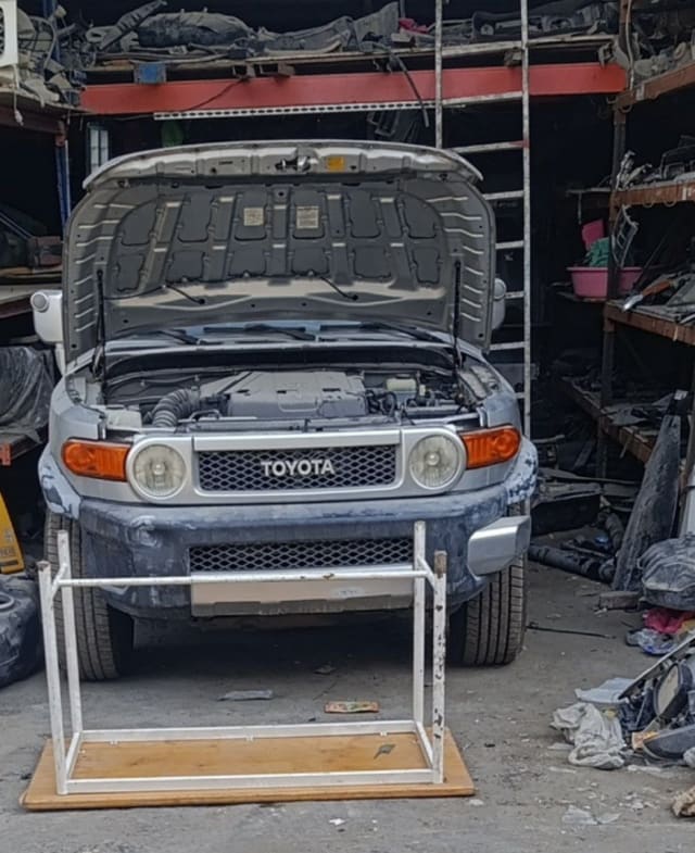 Light grey Toyota FJ Cruiser front halfcut — bumper, grille, headlights and open hood with engine, Sharjah market