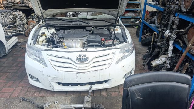 White Toyota Camry sedan front halfcut — bumper, grille, headlights and open engine bay, Sharjah market