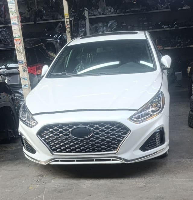 White Hyundai Sonata sedan front end — bumper, mesh grille and headlights, Sharjah market