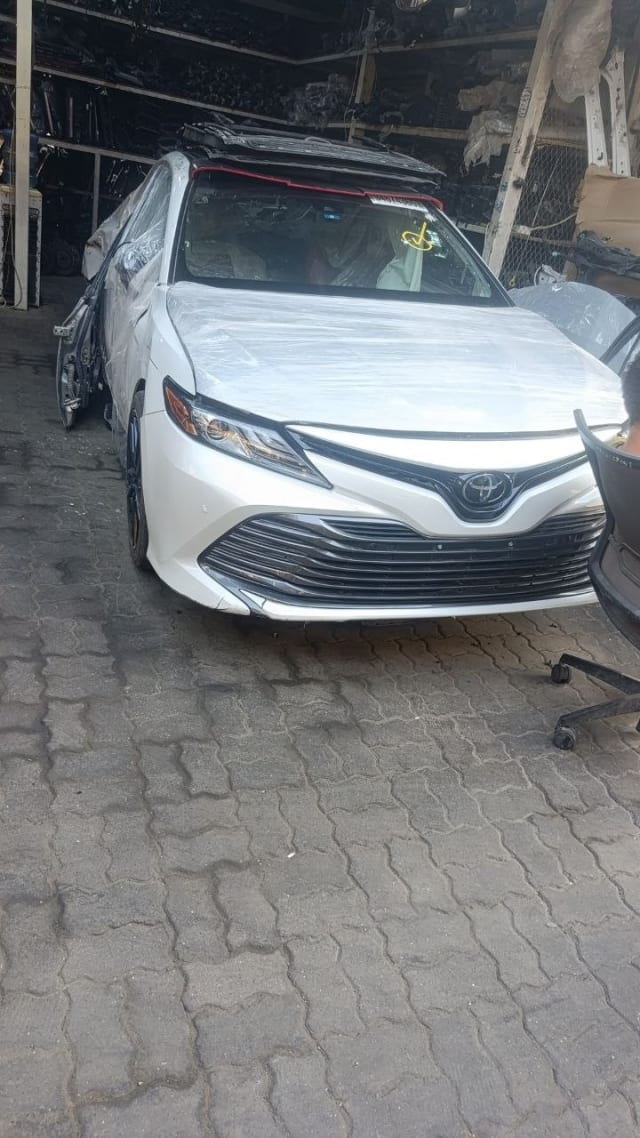 White Toyota Camry sedan front cut — bumper, grille and headlights, Sharjah market