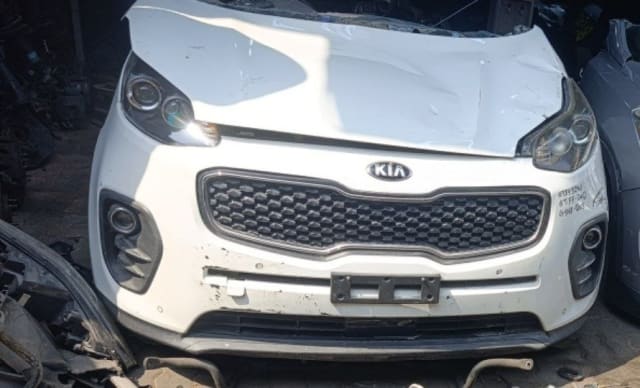 White Kia Sportage front cut — bumper, grille, headlights and fog lamps, damaged hood, Sharjah market