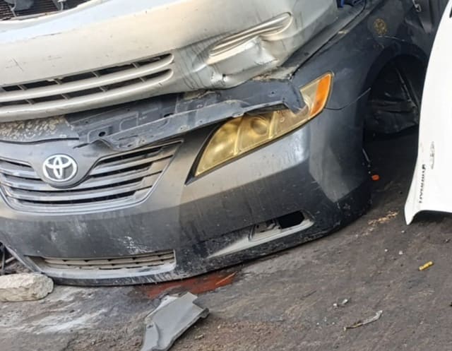 Silver Toyota Camry sedan front cut — grille, badge, yellowed headlight and front bumper, Sharjah market