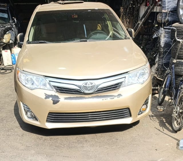 Gold Toyota Camry sedan front end — bumper, chrome grille, headlights and hood, Sharjah market
