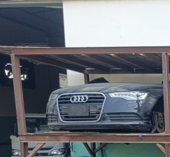 Dark grey Audi A6 sedan front halfcut on rack — bumper, grille and headlights, Sharjah market