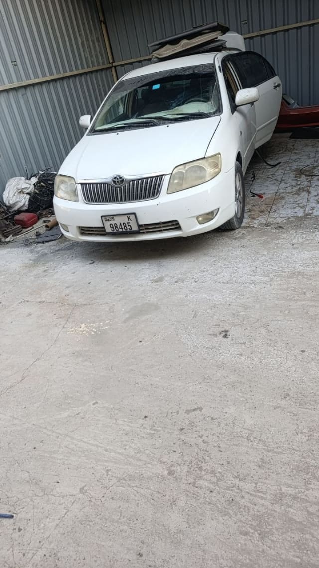 White Toyota Corolla sedan for parts — front bumper, grille and headlights, Sharjah market