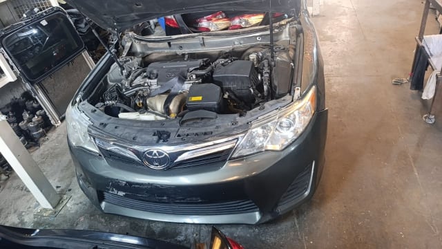 Green Toyota Camry sedan halfcut — front bumper, grille, headlights and open engine bay, Sharjah market
