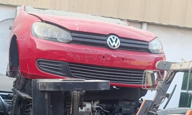 Red Volkswagen Golf front halfcut on a forklift — bumper, grille, headlights and hood, Sharjah market