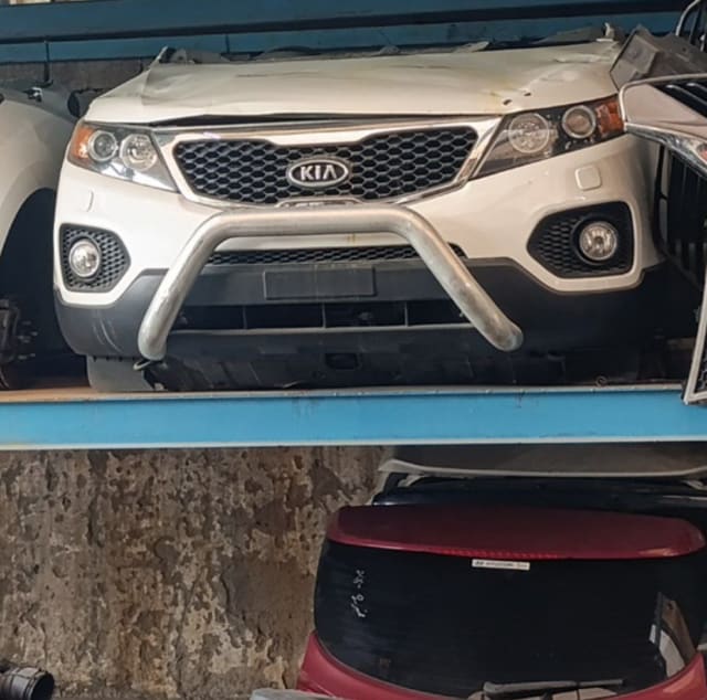 White Kia Sorento front halfcut — bumper, grille, headlights and bull bar on a shelf, Sharjah market