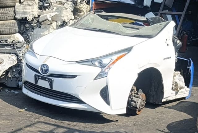 White Toyota Prius front halfcut — bumper, headlights, hood and fender, cracked windshield, Sharjah market