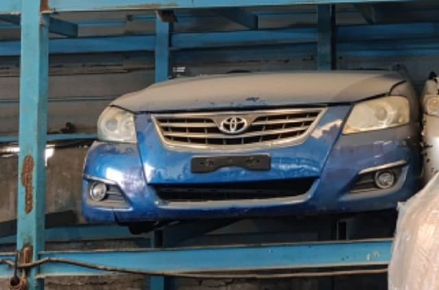 Blue Toyota Aurion front halfcut with bumper, grille, headlights and hood on a rack, Sharjah market