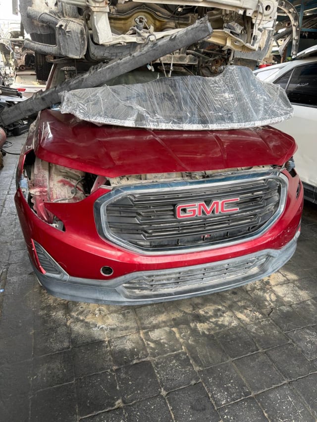 Red GMC Terrain front halfcut with hood, bumper and chrome GMC grille, headlights missing, Sharjah market
