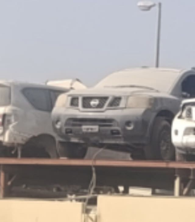 Dusty grey Nissan Pathfinder for parts on a rack — grille, headlights and front bumper, Sharjah market