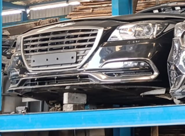 Black Genesis G80 front halfcut — chrome grille, bumper and headlight on a rack, Sharjah market