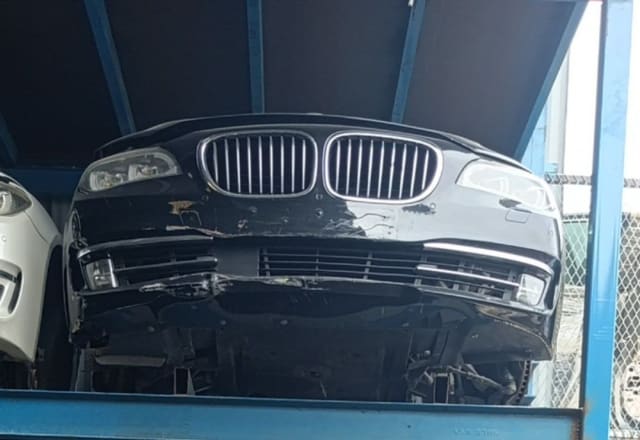 Black BMW 7-Series front halfcut — kidney grille, headlights and scuffed bumper, Sharjah market