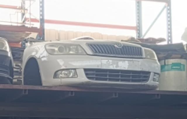 White Skoda Octavia front halfcut with bumper, grille, headlights and fog lights on a rack, Sharjah market