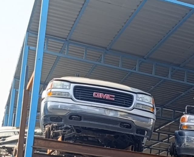 Beige GMC Yukon front halfcut on steel rack, grille, headlights and bumper, Sharjah market