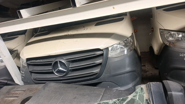 White Mercedes-Benz Sprinter front halfcut with hood, grille, headlights and grey bumper on a rack, Sharjah market