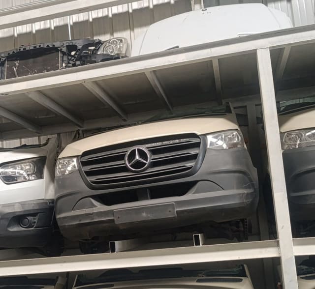 Off-white Mercedes-Benz Sprinter front cut on rack — bumper, grille and headlights, Sharjah market