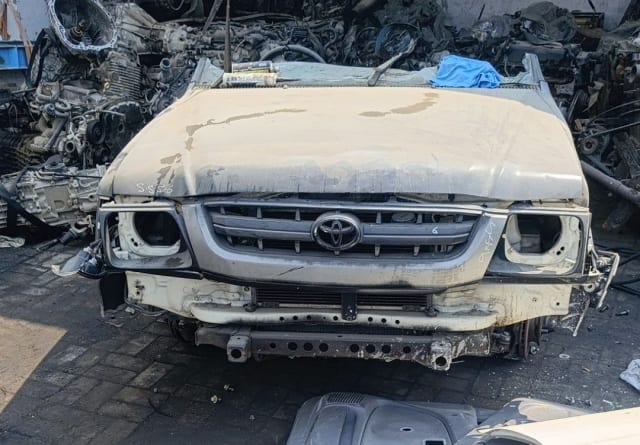 White Toyota Hilux pickup front halfcut — dusty hood, grille and radiator support, Sharjah market