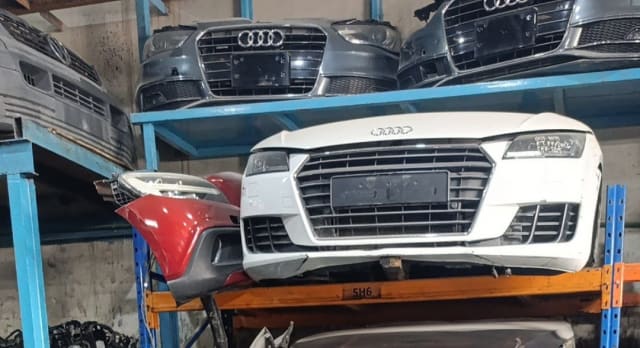 White Audi TT coupe front halfcut with bumper, grille, headlights and hood on a rack, Sharjah market