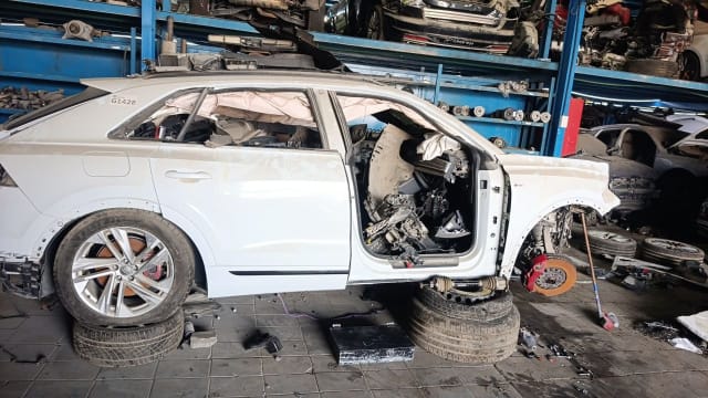 White Audi Q8 halfcut side view: rear door, alloy wheel, red brake caliper and driveshaft, Sharjah market