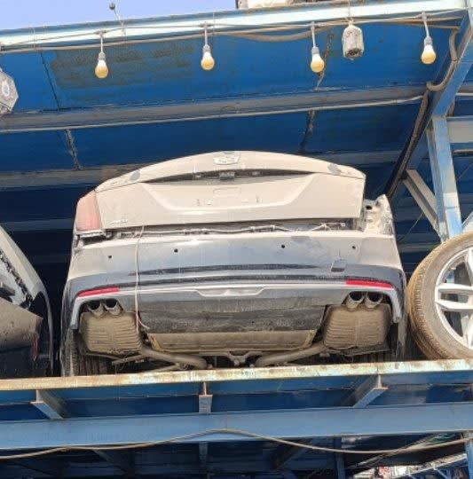 Dusty dark grey Cadillac CT6 rear halfcut on a rack — trunk lid, rear bumper, quad exhausts, Sharjah market