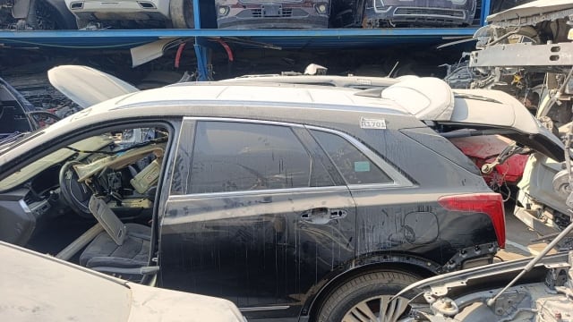 Black Cadillac XT5 SUV halfcut side view with rear door, quarter panel and taillight, Sharjah market