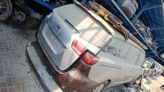 Silver Kia Carnival minivan for parts, rear view with tailgate, tail lights and removed bumper, Sharjah market