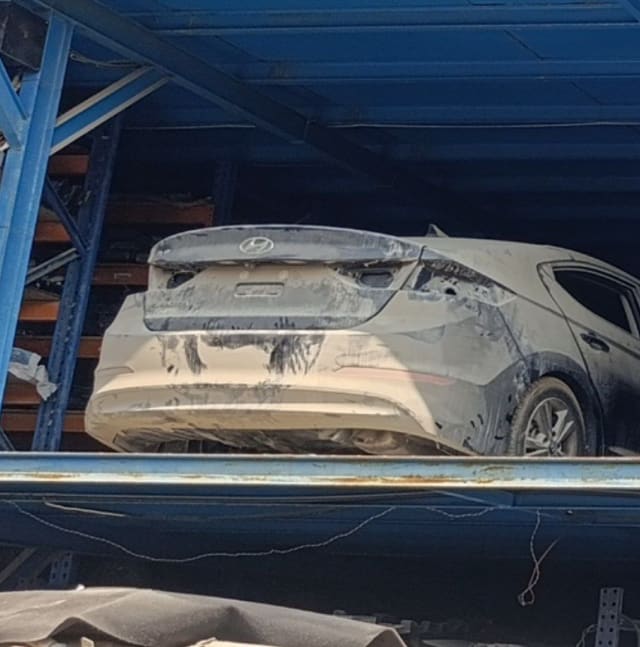 Dusty Hyundai Elantra sedan rear on a storage rack, trunk lid, bumper and quarter panel, Sharjah market