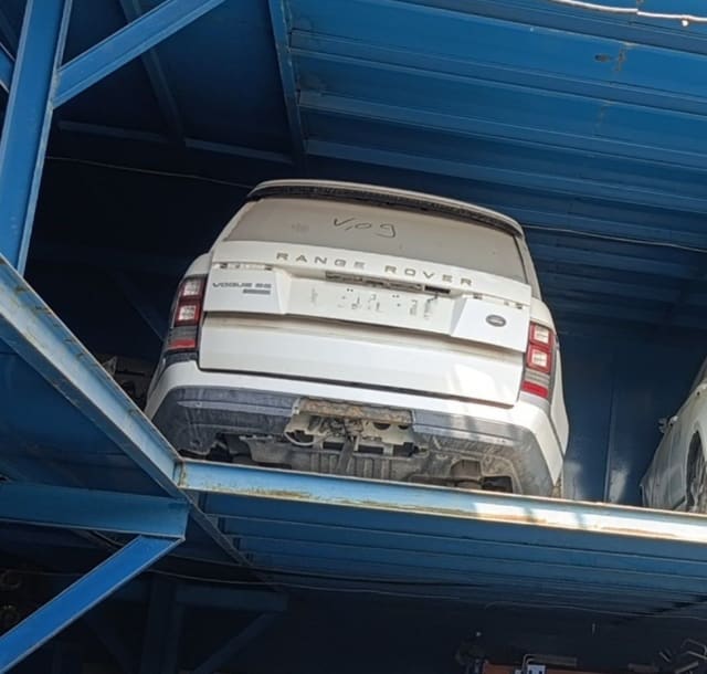 White Land Rover Range Rover Vogue SE rear: tailgate, tail lights and bumper on a rack, Sharjah market