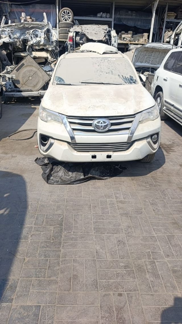 White Toyota Fortuner halfcut front view: bumper, chrome grille, headlights and hood, Sharjah market