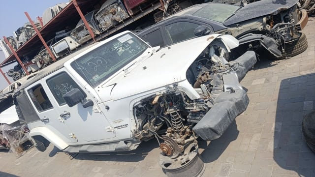 White Jeep Wrangler Unlimited Sahara for parts with stripped front end and exposed suspension, Sharjah market
