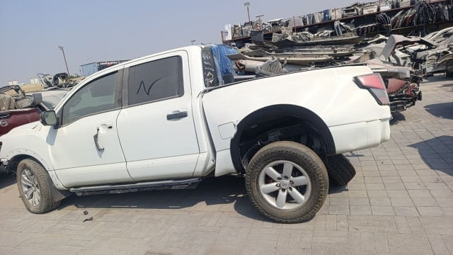 White Nissan Titan crew cab pickup for parts, side view — doors, bed, taillight and alloy wheels, Sharjah market