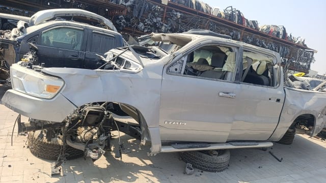 Silver RAM 1500 pickup for parts, side view: bumper, headlight, fender, doors, crushed roof, Sharjah market