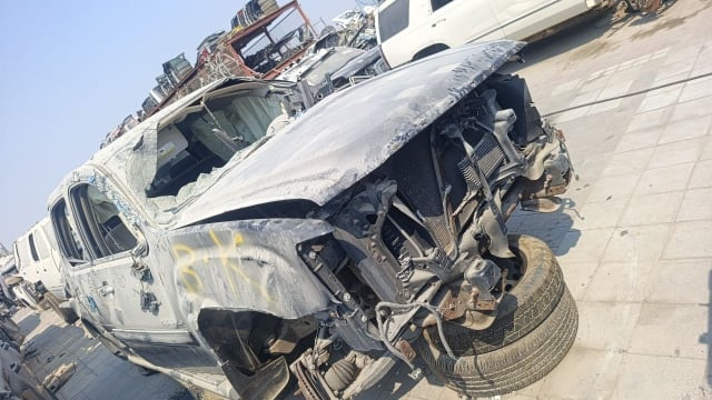 Silver GMC Yukon Denali car for parts — crushed hood, exposed radiator, suspension and wheel, Sharjah market