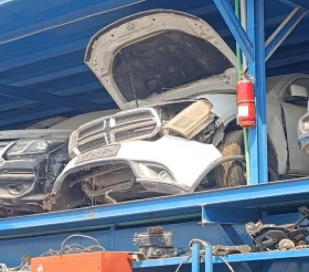 White Dodge Durango SUV halfcut on a rack, hood open, with grille, bumper and headlight, Sharjah market