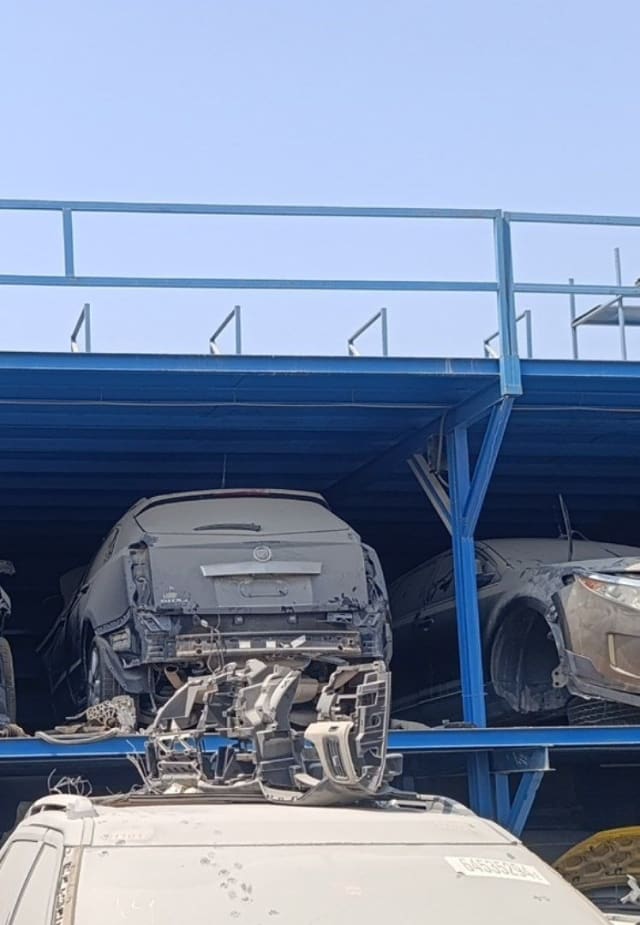 Dusty Cadillac SRX car for parts, rear view on rack — tailgate and quarter panels, bumper removed, Sharjah