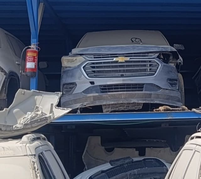 Dark grey Chevrolet Traverse for parts on a rack: grille, bumper and hood, front-right damage, Sharjah market