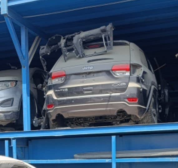 Dark grey Jeep Grand Cherokee halfcut rear: tailgate, taillights, rear bumper on rack, Sharjah market
