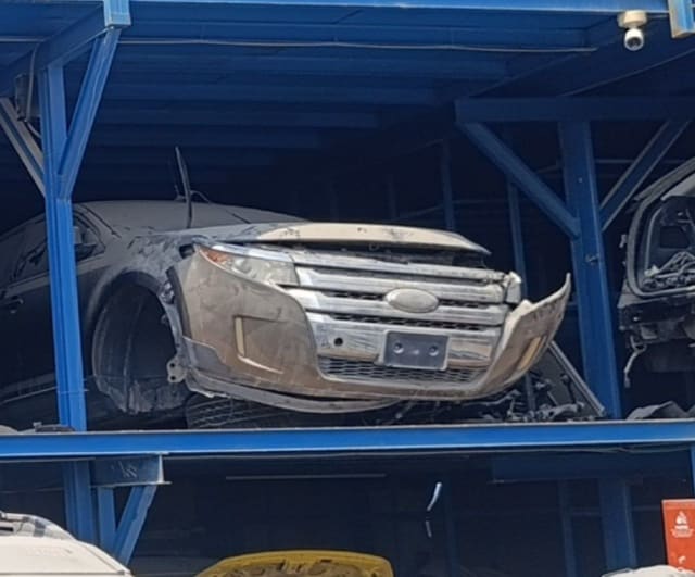 Dusty Ford Edge halfcut on a rack — chrome grille, headlights, loose front bumper and hood, Sharjah market