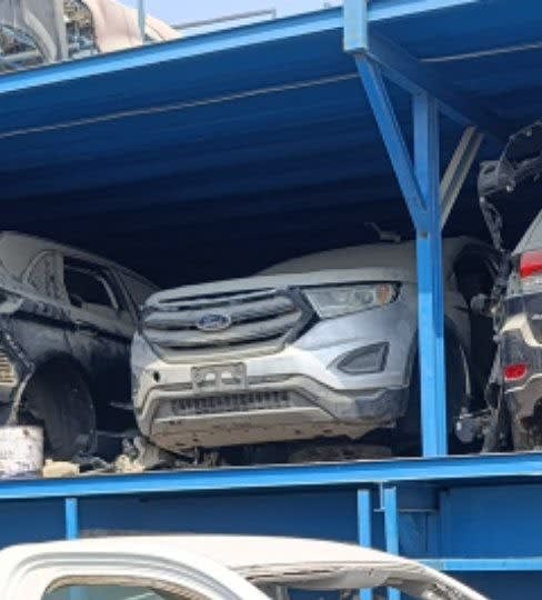 Silver Ford Edge SUV car for parts on a rack — front bumper, grille and headlights, Sharjah market