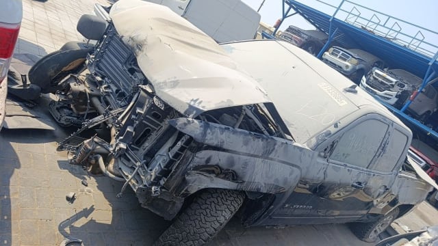 Black Chevrolet Silverado pickup for parts — damaged front end, crumpled hood and exposed engine bay, Sharjah market