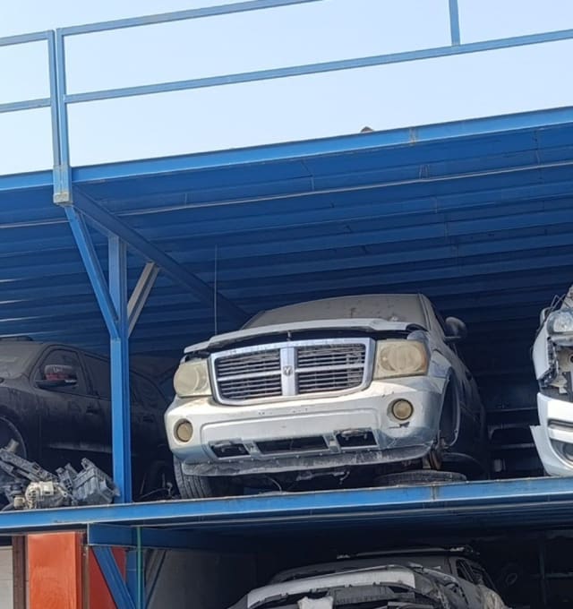 Silver Dodge Durango car for parts on a storage rack, with grille, headlights and bumper visible, Sharjah market