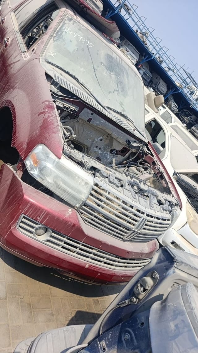 Dark red Lincoln Navigator for parts — chrome grille, headlights, bumper, hood off, Sharjah market