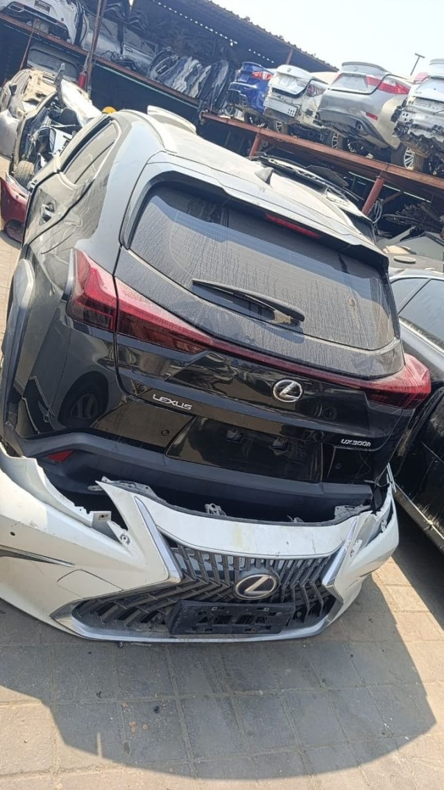 Black Lexus UX300h rear halfcut with tailgate and tail lights, white front bumper in front, Sharjah market